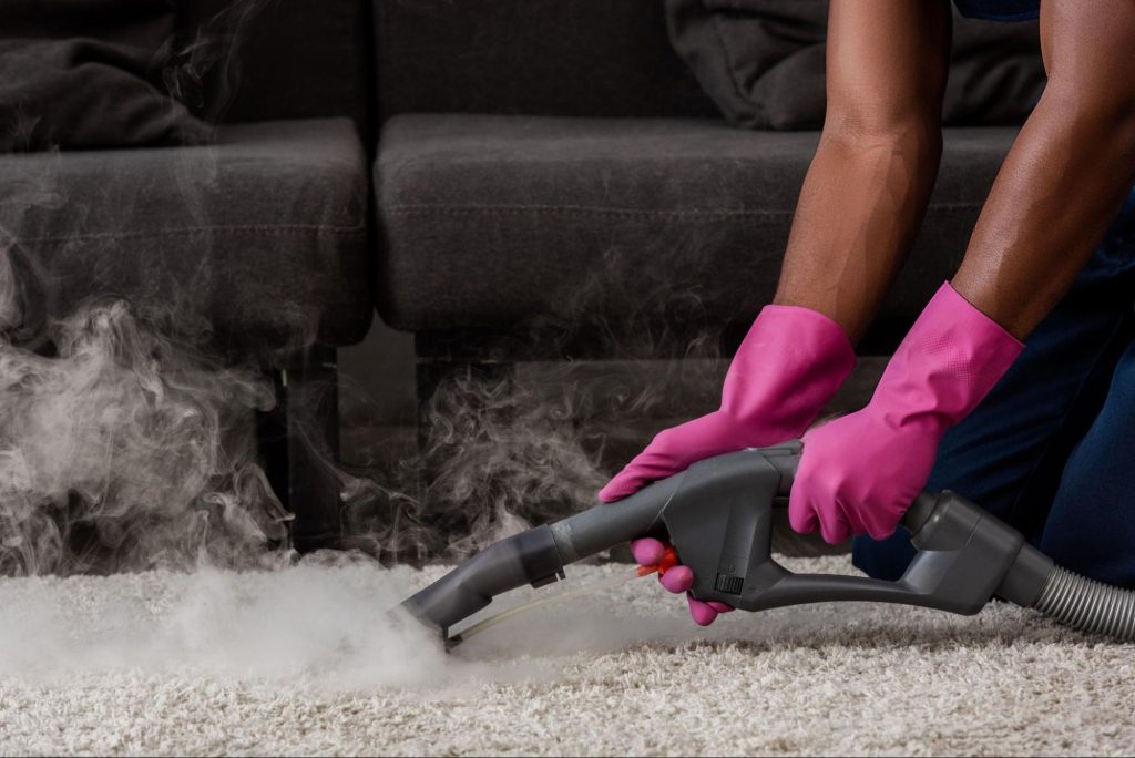 Uma pessoa limpando um carpete com uma máquina que produz vapor.
