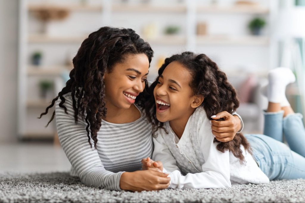 Uma mãe e filha deitadas sobre um tapete.