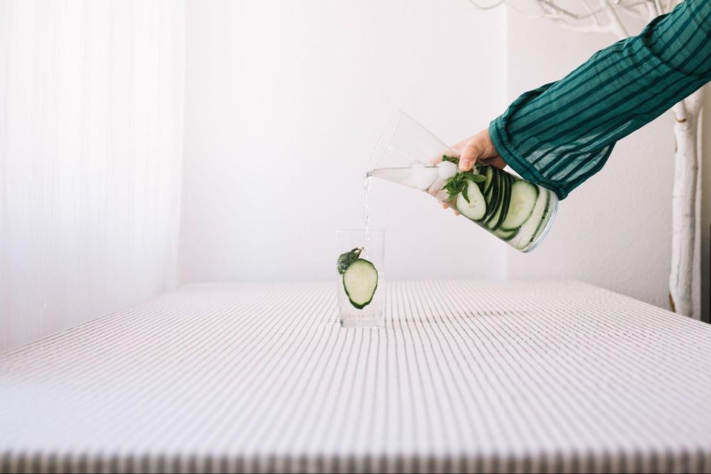 Um colchão, sobre ele um copo e uma jarra.