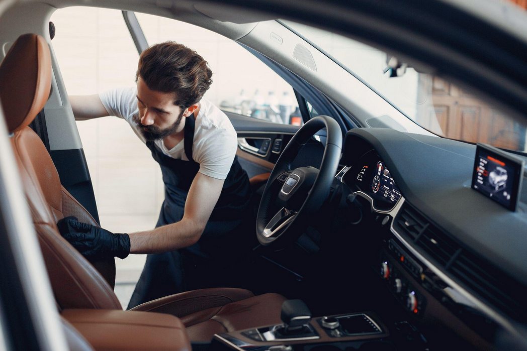 Um profissional limpando o estofado do banco de um carro