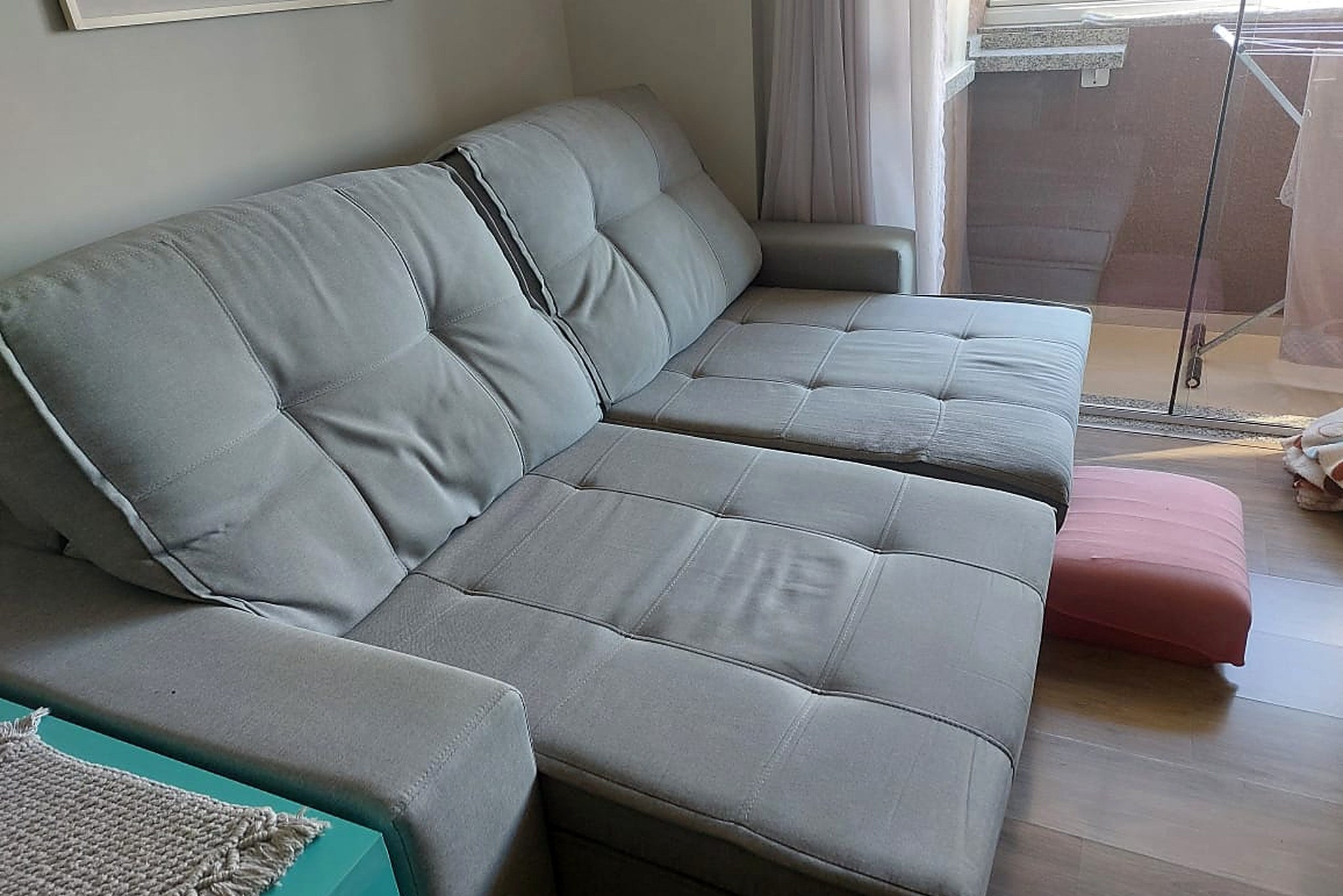 Sofá de tecido claro em sala com janela e sacada abertas