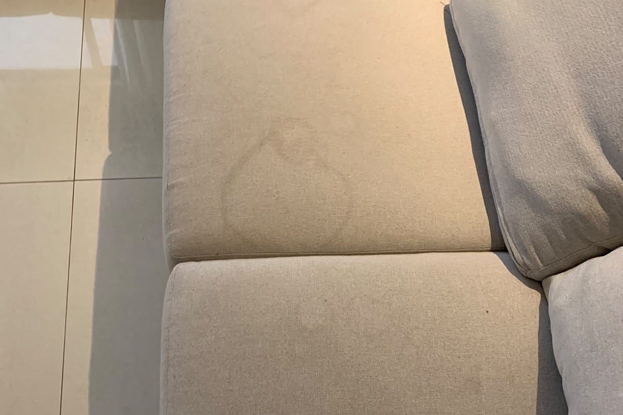 Assento de sofá de tecido claro com marca amarelada de xixi de pet